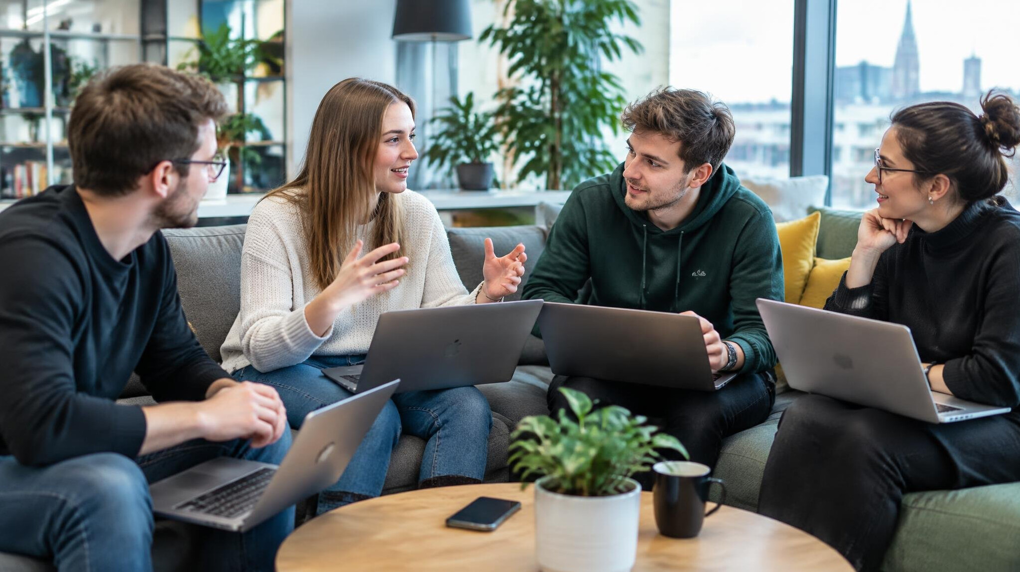 People chatting and discussing on laptops in a casual meeting space